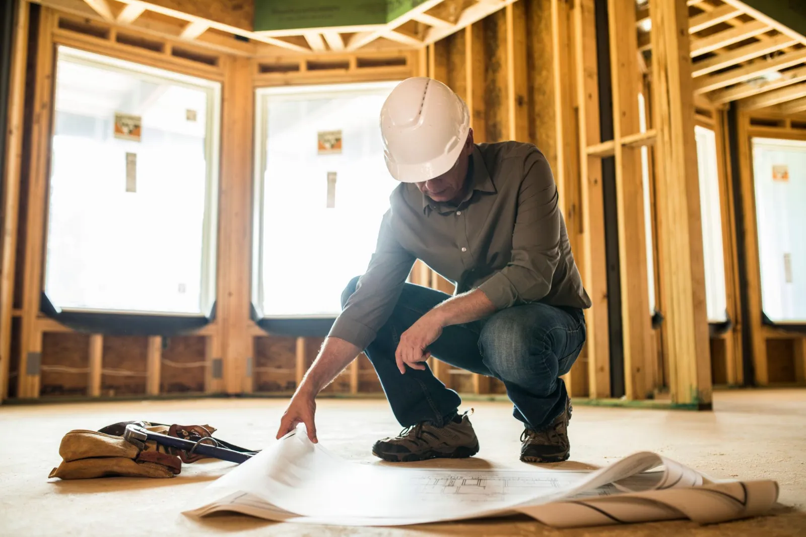 Contractor reviewing plans inside a framed house