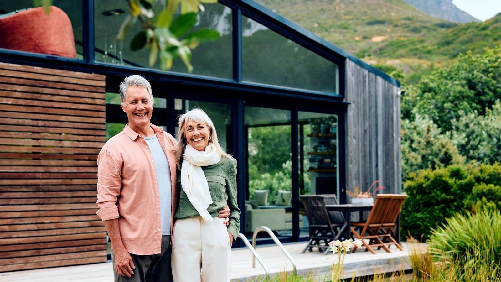 Retired couple standing in front of their home