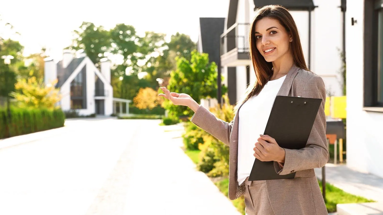 Real estate agent holding keys in front of a house