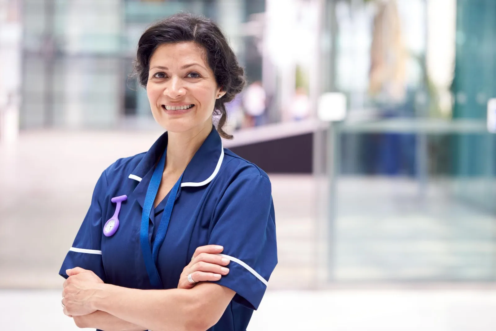 Travel nurse in scrubs smiling at the hospital where she works