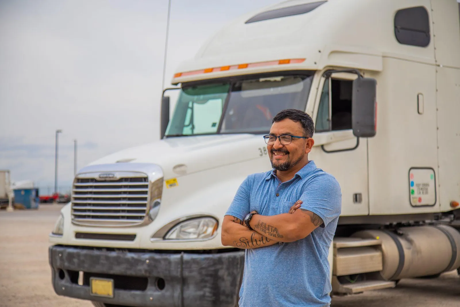 Trucker with arms crossed in front of his truck